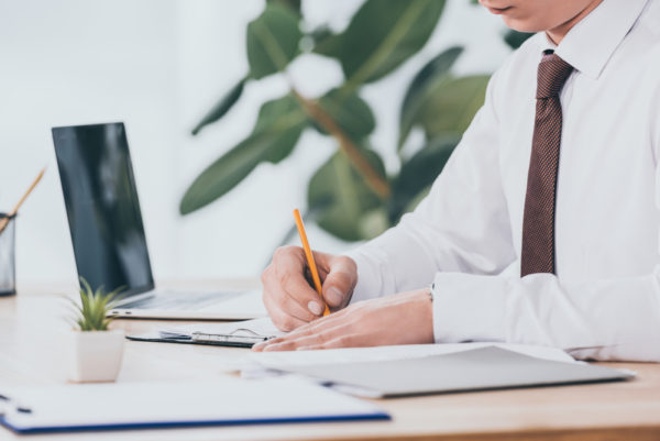 businessman-writing-in-document-at-workplace.